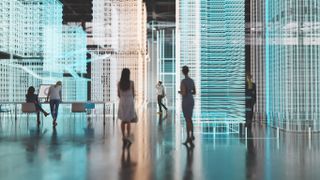 Workers walking around a large warehouse with structures presented in holograms, denoting a digital workplace