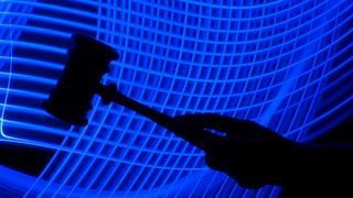 A photo of a silhouette of a hand holding a gavel is in the foreground, with a futuristic mesh of blue lines in the background