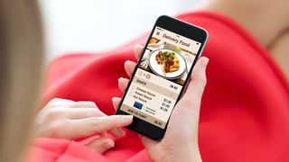 A woman looking at food on a delivery app on her smartphone