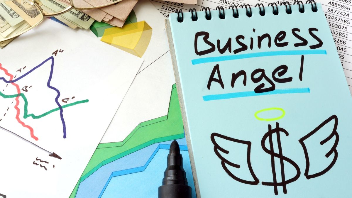 A close up of various papers spread across a desk, including a notepad with the words &#039;business angel&#039;