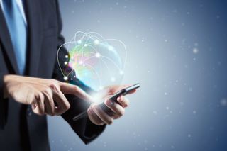 Business man using phone as global netowrking graphic appears above his hand