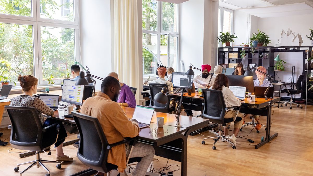 Software developers sitting at desks using Ai tools in an open plan office space.