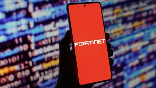 Fortinet logo is displayed on a smartphone screen in front of code background