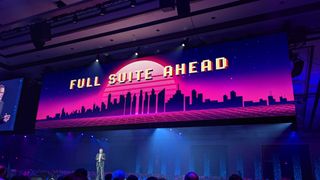 A wide-angle shot of NetSuite EVP Gary Wiessinger, giving a keynote speech with a large screen above displaying "FULL SUITE AHEAD" in retro arcade letters