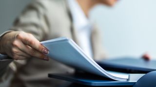 A business woman holding a stack of papers that have just been printed