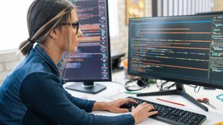 Software developer using code generation tool on computer workstation.