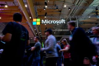 Attendees walk past the logo of US multinational technology company Microsoft during the Web Summit in Lisbon on November 6, 2019