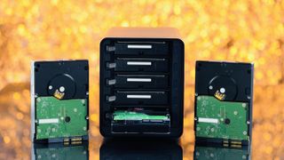 A NAS drive and hard disks against a yellow background