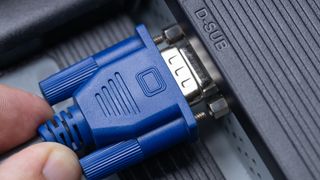 Somebody connecting a VGA cable into a desktop computer