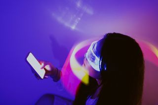 Woman wearing VR headset while holding smartphone