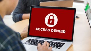 A laptop screen showing "access denied" text on a red background