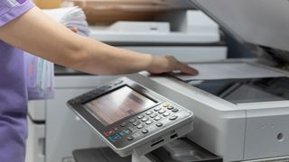 An employee reaches into the scanner section of a laser printer