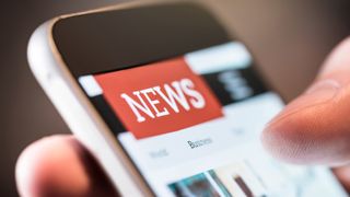 A person holding a smartphone in their hand looking at the news