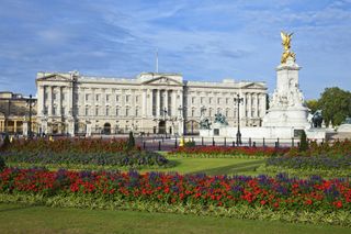 A photo of the Queen Victoria Memorial with Buckingham Palace in the background on a bright sunny day