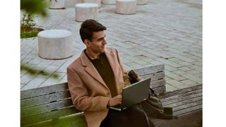 man with brown jacket sitting on bench
