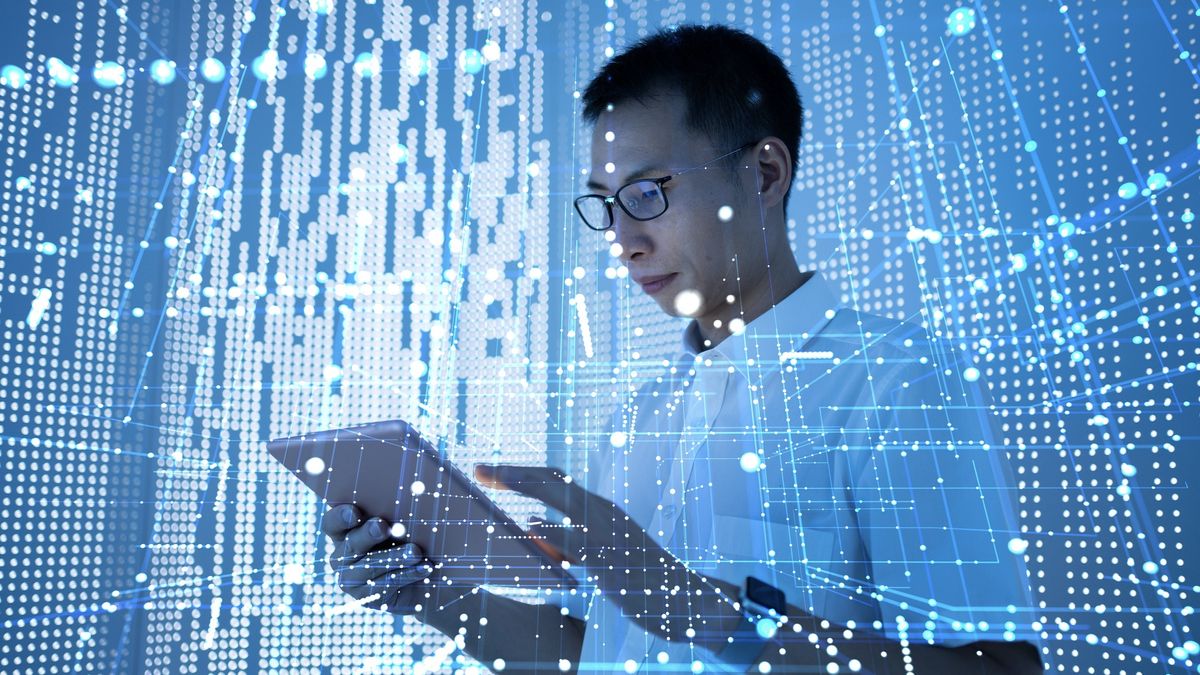 A businessman looking at a tablet in front of an abstract background of blue lines and dots